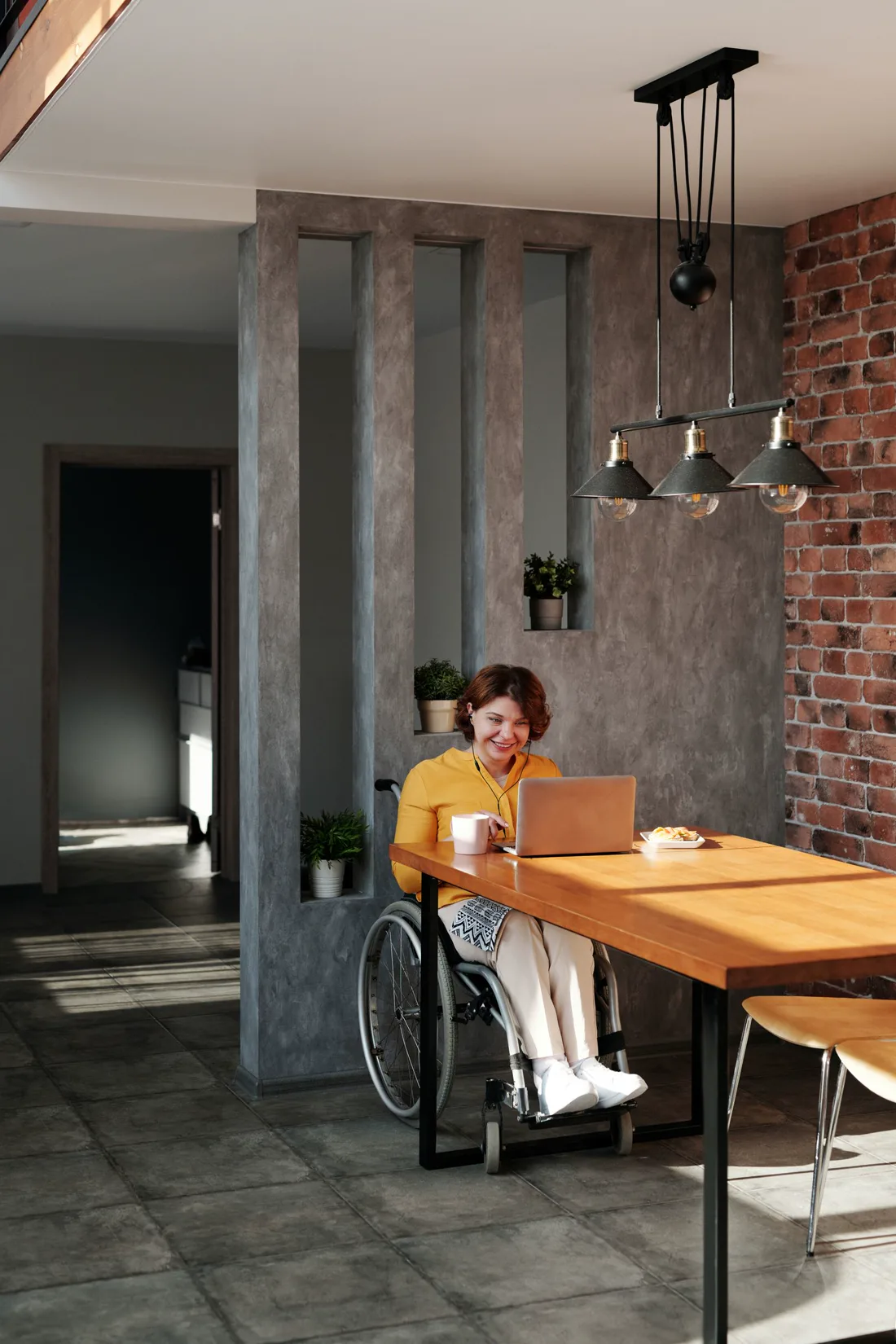 A wheelchair user working independently on a laptop at home
